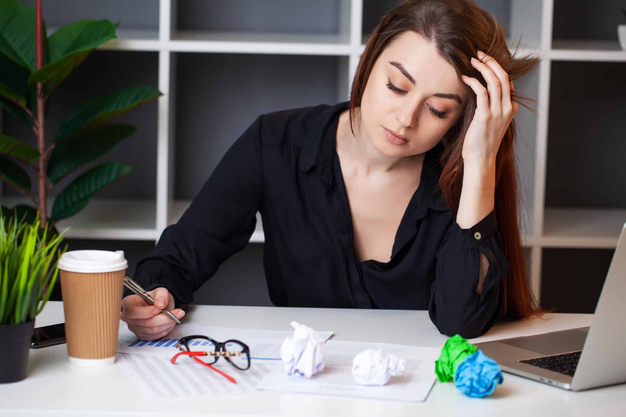 Fehler vermeiden im Business der Ernährungsberatung - traurige Geschäftsfrau im Büro, die am Laptop arbeitet