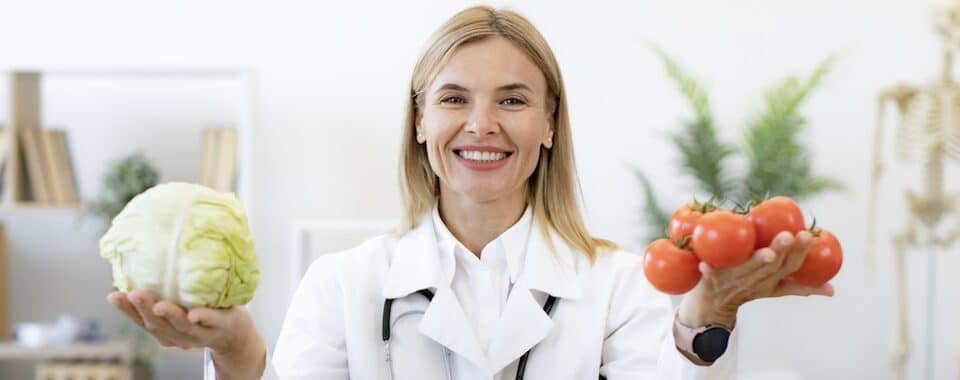 Spezialisierungen als Ernährungsberater - Der Weg zum Experten - Ernährungsberaterin hält frisches Gemüse und Obst in die Kamera