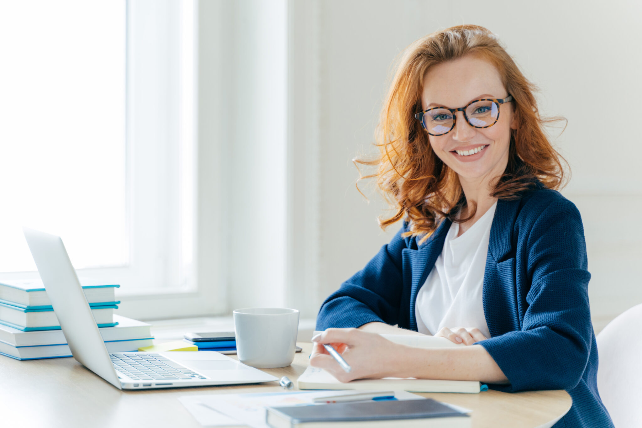 Frau sitzt am Schreibtisch mit Laptop und Büchern und macht Notizen - Finde dein Konzept der Ernährungsberatung
